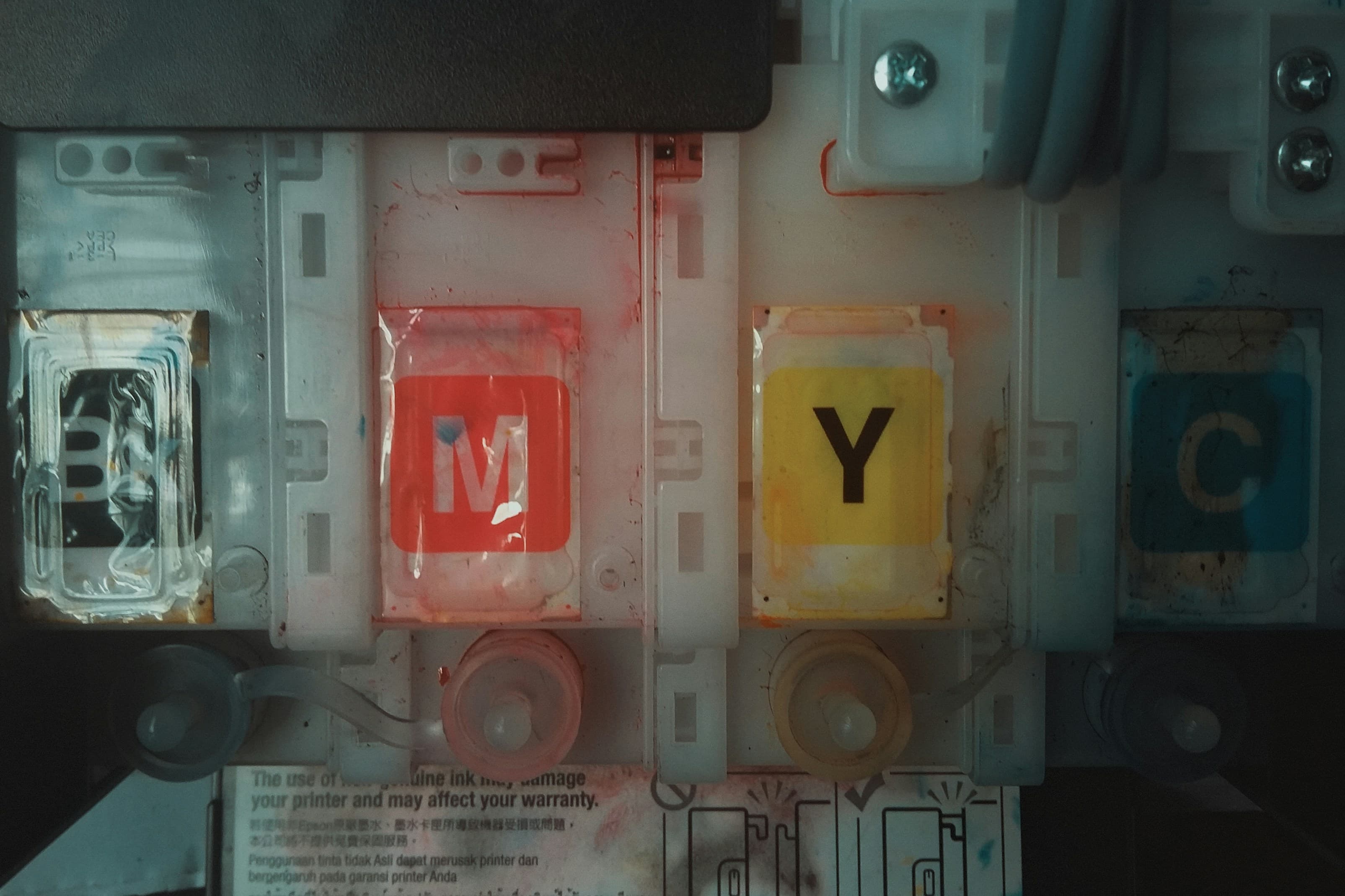 CMYK ink cartridges labelled M, Y, C and K inside a printer